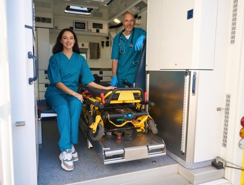 Man and woman in medical uniforms are inside an ambulance